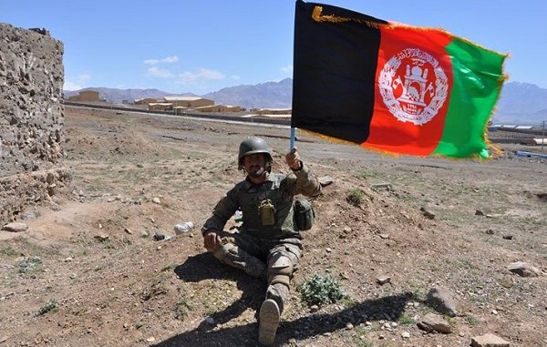 Afghan Soldier holds Afghan flag.