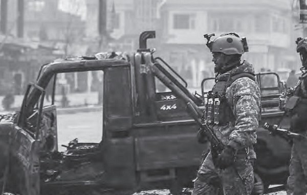 Afghan security force members walk past a bombed truck in Kabul (AFP photo by Zakeria Hashimi)